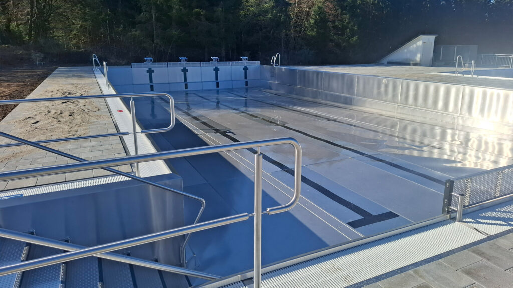 Modernes Schwimmerbecken im Bau mit Edelstahl und Umgebung